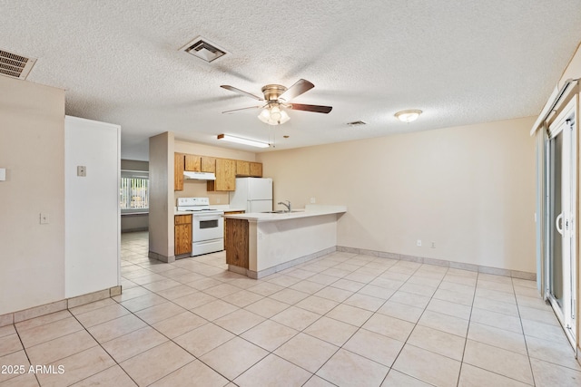 kitchen featuring visible vents, under cabinet range hood, white appliances, a peninsula, and light countertops