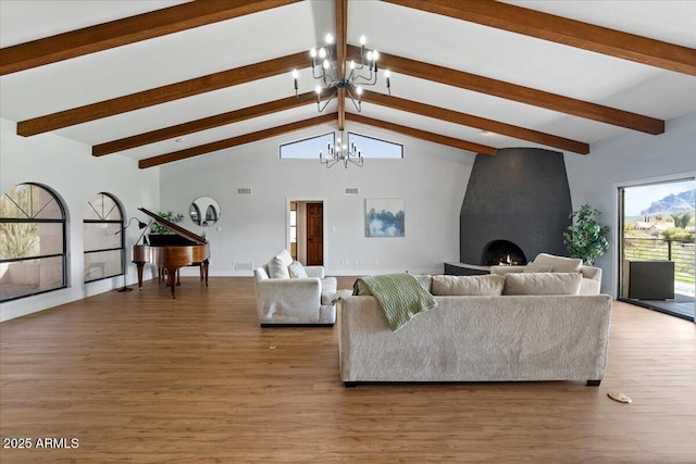 living room with beam ceiling, wood-type flooring, a fireplace, and a chandelier