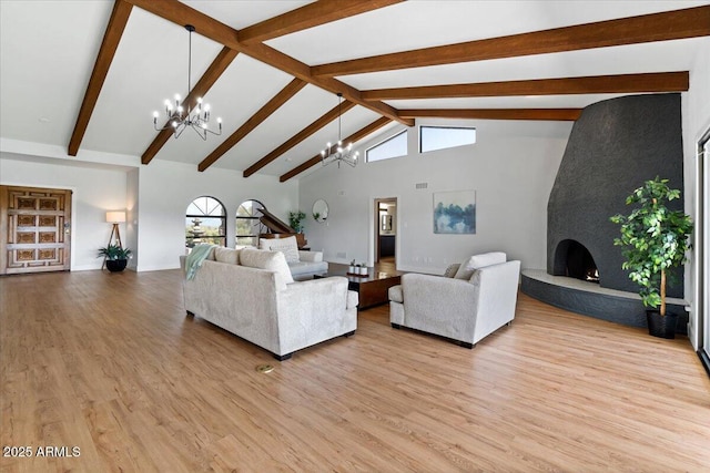 living room with a fireplace, beam ceiling, light wood-type flooring, and high vaulted ceiling