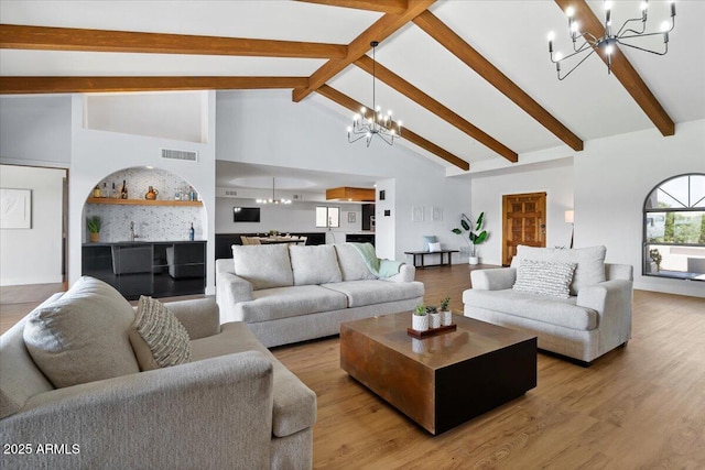 living room with beamed ceiling, hardwood / wood-style floors, high vaulted ceiling, and an inviting chandelier