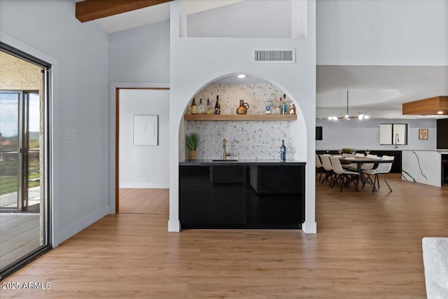 kitchen featuring beam ceiling, light wood-type flooring, plenty of natural light, and sink