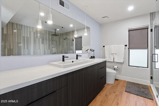 bathroom featuring wood-type flooring, vanity, toilet, and an enclosed shower