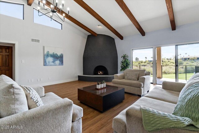 living room with a fireplace, hardwood / wood-style floors, lofted ceiling with beams, and a chandelier