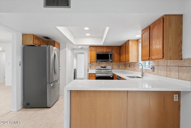 kitchen featuring kitchen peninsula, a raised ceiling, appliances with stainless steel finishes, light tile patterned floors, and sink