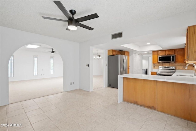 kitchen featuring stainless steel appliances, a textured ceiling, sink, and kitchen peninsula