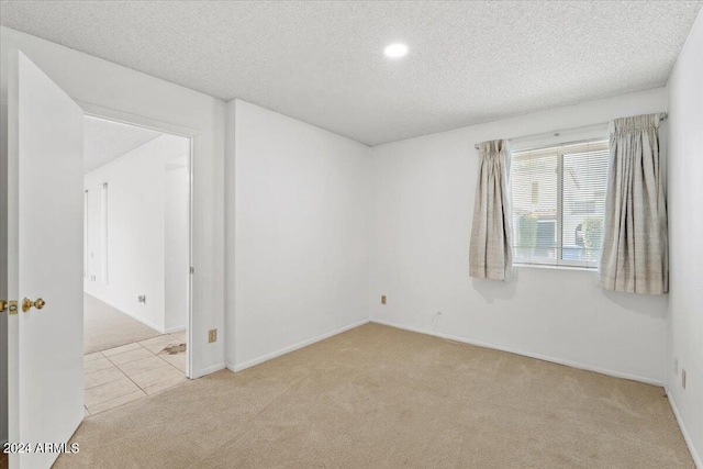 spare room featuring light carpet and a textured ceiling