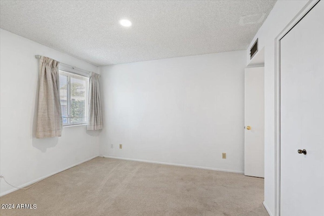 unfurnished bedroom with a closet, light carpet, and a textured ceiling