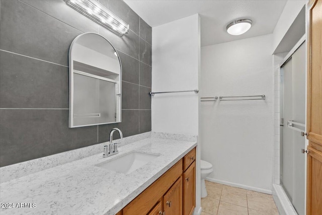 bathroom with vanity, toilet, tile patterned floors, and an enclosed shower