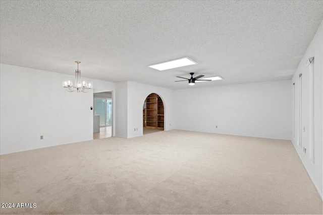 unfurnished living room with a textured ceiling, light colored carpet, and ceiling fan with notable chandelier