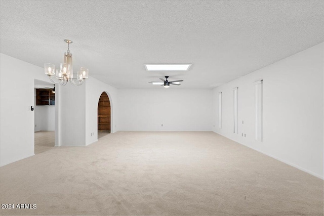 empty room with a textured ceiling, light colored carpet, and ceiling fan with notable chandelier