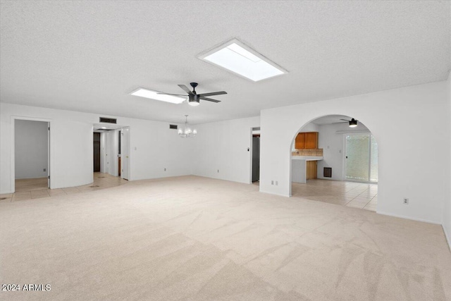 unfurnished living room featuring light carpet, a textured ceiling, and ceiling fan with notable chandelier