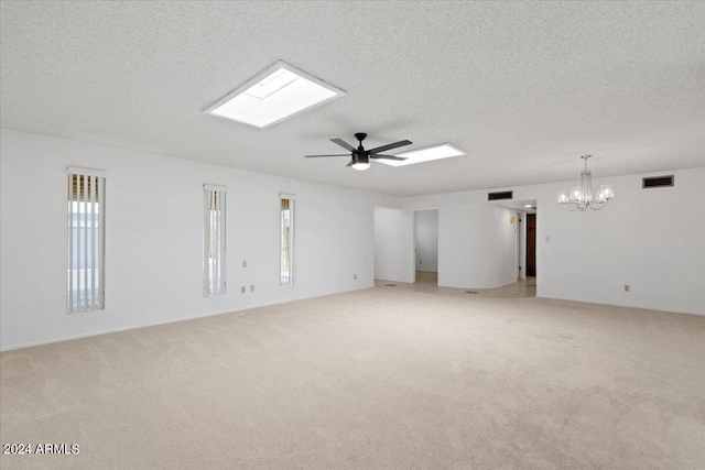 spare room featuring light carpet, a textured ceiling, a wealth of natural light, and ceiling fan with notable chandelier