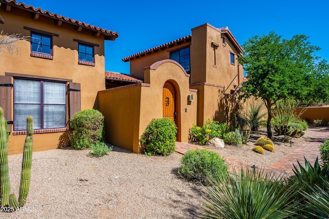 mediterranean / spanish-style house with fence, a tiled roof, and stucco siding