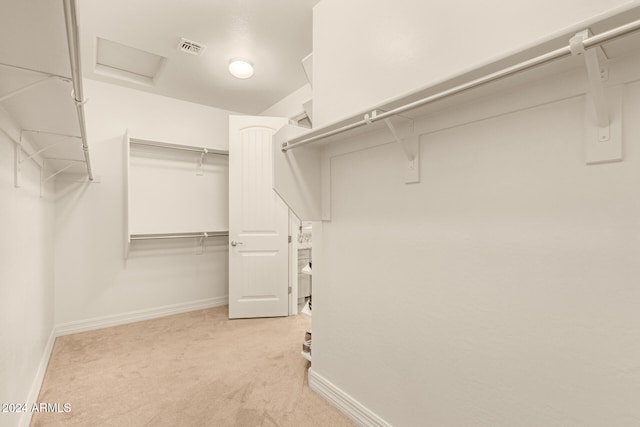 walk in closet with light colored carpet