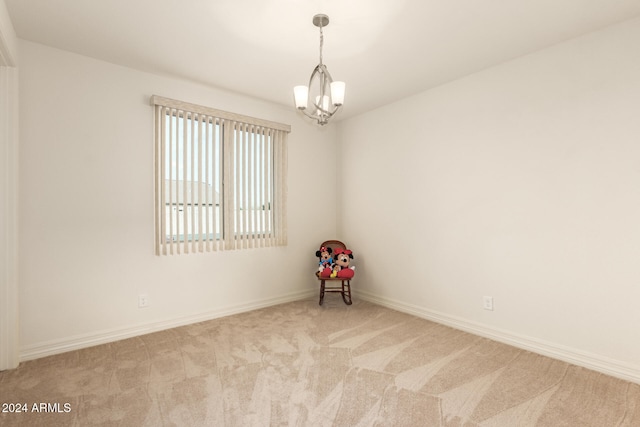 empty room with light carpet and a chandelier