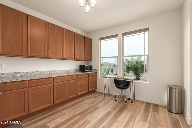 office featuring built in desk, light hardwood / wood-style flooring, and a healthy amount of sunlight