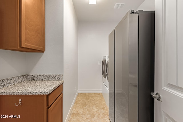 washroom with washing machine and clothes dryer, light tile patterned flooring, and cabinets