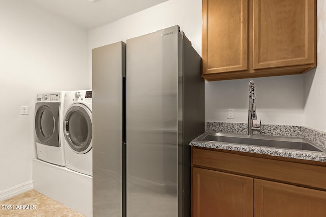 laundry area featuring cabinets, light tile patterned floors, washer and clothes dryer, and sink