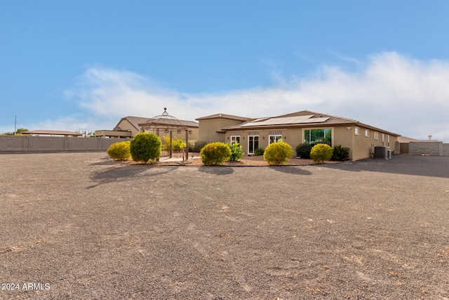 view of front of home featuring central AC unit and solar panels