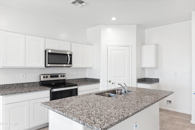 kitchen with white cabinetry, sink, a center island with sink, appliances with stainless steel finishes, and dark stone countertops