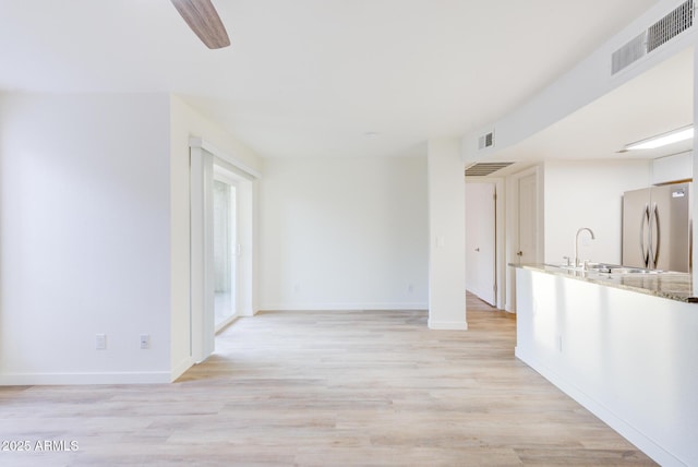 unfurnished living room with sink and light hardwood / wood-style flooring