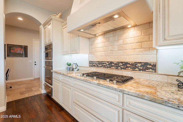1617 E Copper Holw, Queen Creek, AZ 85140 - kitchen with arched walkways, dark wood-type flooring, backsplash, light stone counters, and stainless steel gas cooktop