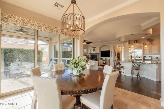 1617 E Copper Holw, Queen Creek, AZ 85140 - dining space featuring ceiling fan, arched walkways, a chandelier, crown molding, and a fireplace
