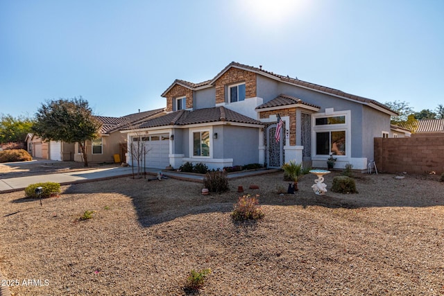 view of front of home featuring stucco siding, an attached garage, fence, driveway, and a tiled roof