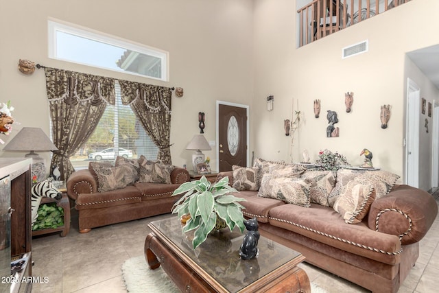 living area with a towering ceiling, light tile patterned floors, and visible vents