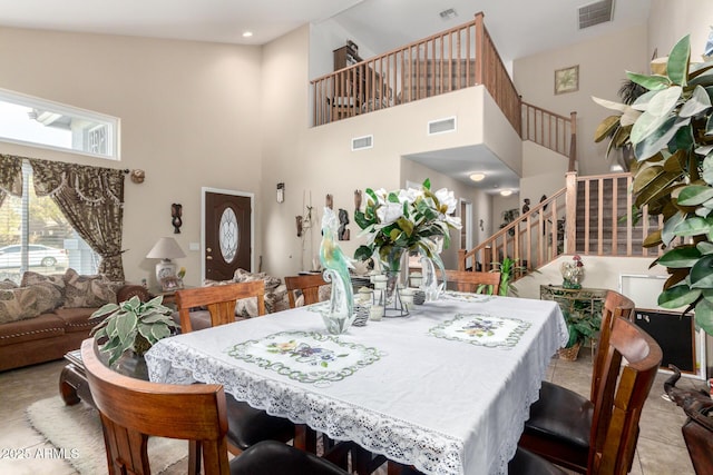 dining space featuring stairs, a towering ceiling, and visible vents