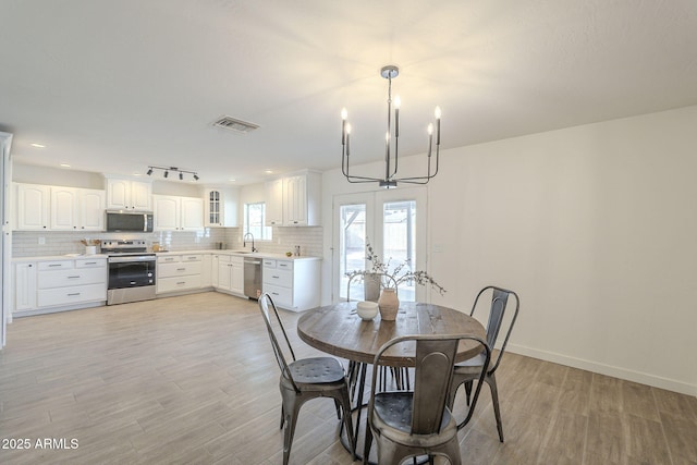 dining space featuring light wood-type flooring, french doors, visible vents, and baseboards