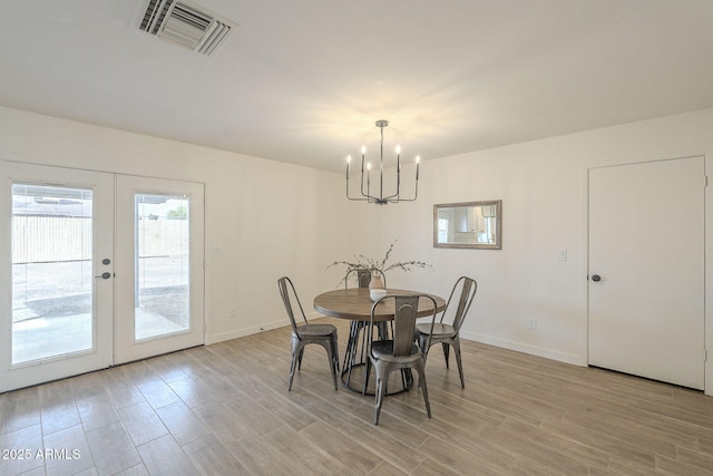 dining space featuring a chandelier, light wood-style flooring, visible vents, baseboards, and french doors