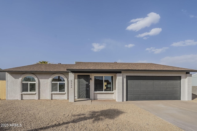 ranch-style house featuring a garage, concrete driveway, and a shingled roof