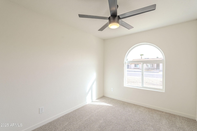 carpeted spare room with ceiling fan and baseboards