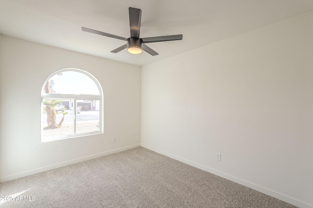 carpeted spare room featuring ceiling fan and baseboards