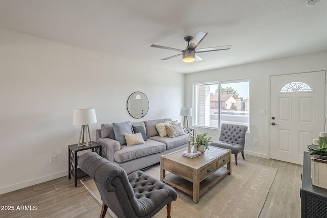 living room with light wood finished floors, baseboards, and a ceiling fan