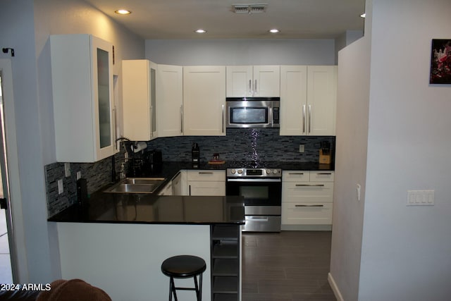 kitchen with kitchen peninsula, white cabinetry, sink, and appliances with stainless steel finishes