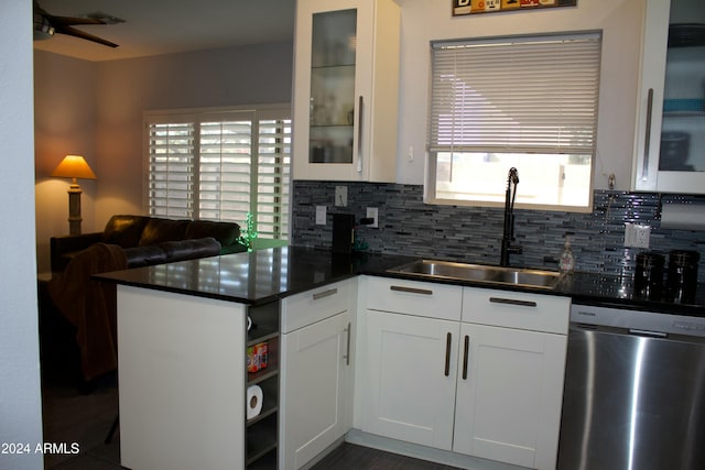 kitchen with backsplash, kitchen peninsula, sink, stainless steel dishwasher, and white cabinetry