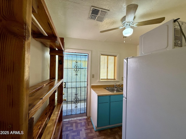 kitchen with ceiling fan, sink, dark parquet floors, white refrigerator, and a textured ceiling