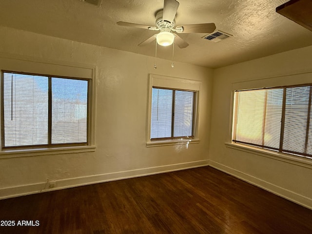 empty room with a textured ceiling, ceiling fan, and dark hardwood / wood-style floors