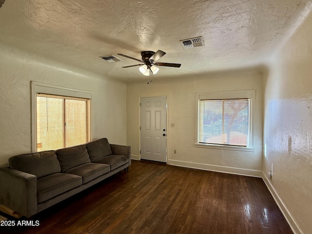 living room featuring a textured ceiling, ceiling fan, and dark hardwood / wood-style floors