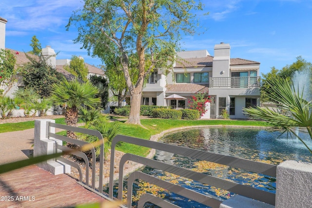 back of property with a balcony and a water view