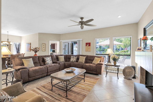 tiled living room with ceiling fan with notable chandelier