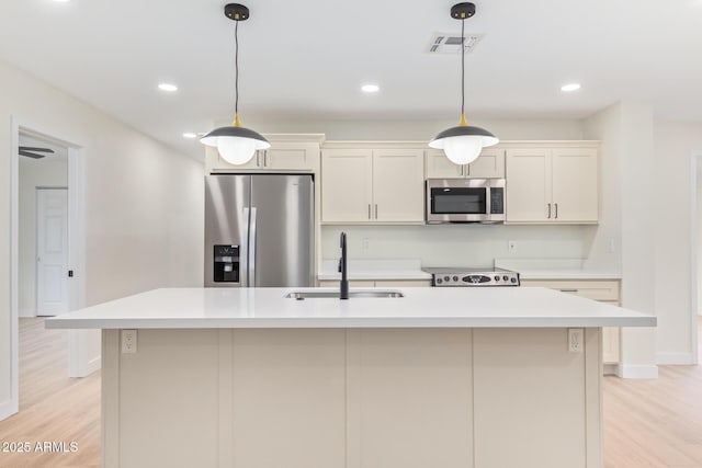 kitchen with a center island with sink, stainless steel appliances, light countertops, visible vents, and a sink