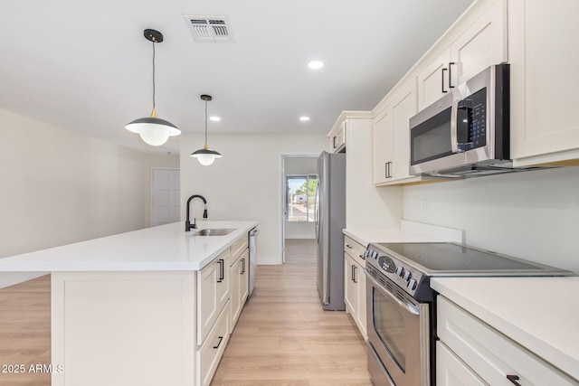 kitchen featuring a center island with sink, visible vents, stainless steel appliances, light countertops, and a sink