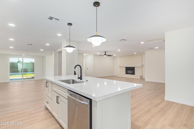 kitchen featuring a sink, visible vents, open floor plan, stainless steel dishwasher, and a brick fireplace