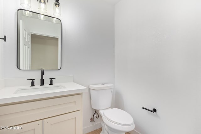 bathroom with toilet, baseboards, and vanity