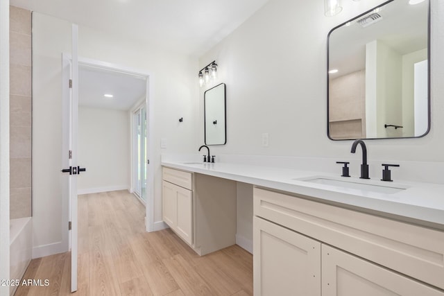 full bath featuring double vanity, visible vents, a shower, wood finished floors, and a sink