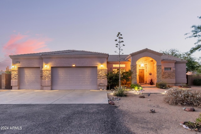 view of front of home with a tile roof, stucco siding, concrete driveway, a garage, and stone siding