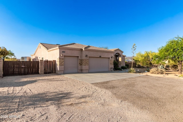 view of front of property with driveway, a tiled roof, an attached garage, fence, and stucco siding